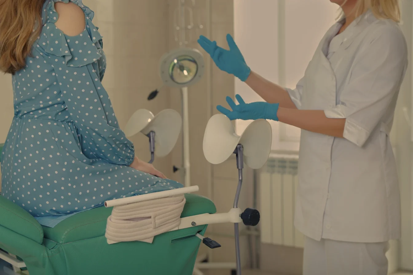 Imagen de una doctora especializada en ginecología junto a su paciente que se encuentra sentada en una camilla durante una consulta rutinaria